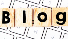 The word blog arranged from wooden blocks placed on a white computer keyboard.