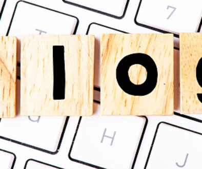 The word blog arranged from wooden blocks placed on a white computer keyboard.